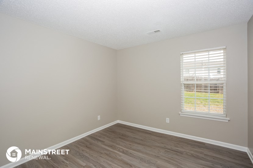 the interior of an empty room with wood floors and a window