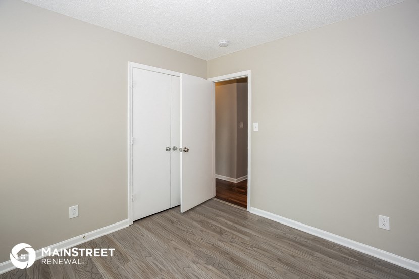 the living room of an apartment with a door to the hallway and a closet