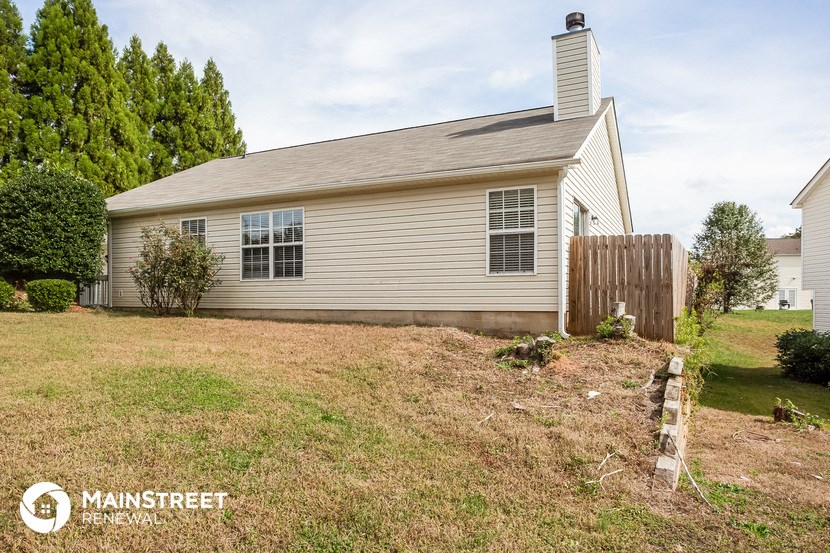 a small house with a yard and a wooden fence
