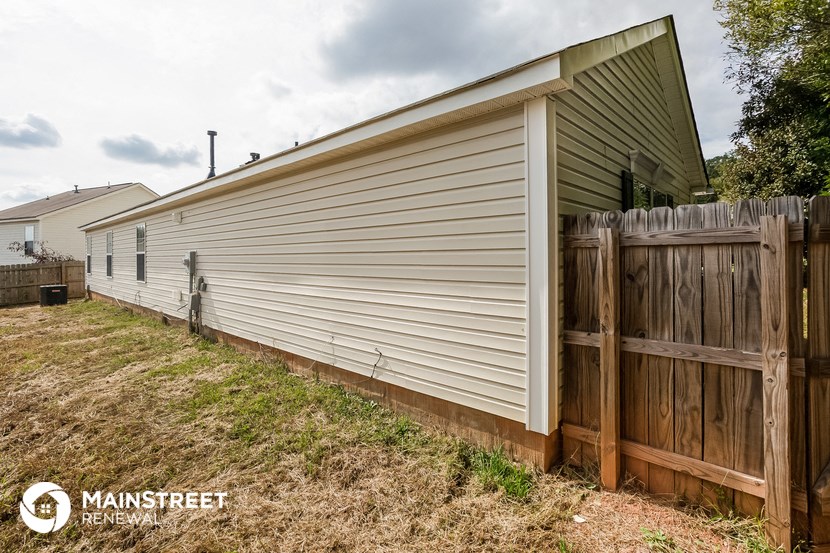 the backyard of a home with a wooden fence and a detached garage