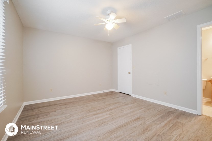 the spacious living room with wood flooring and a ceiling fan