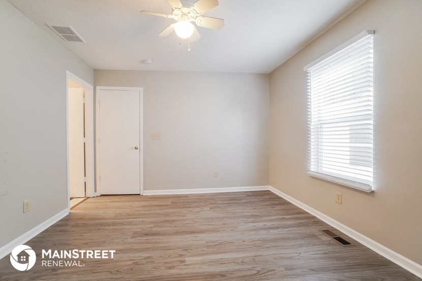 the spacious living room with wood flooring and white walls