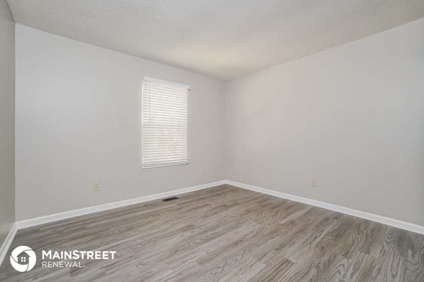 the spacious living room with wood flooring and white walls