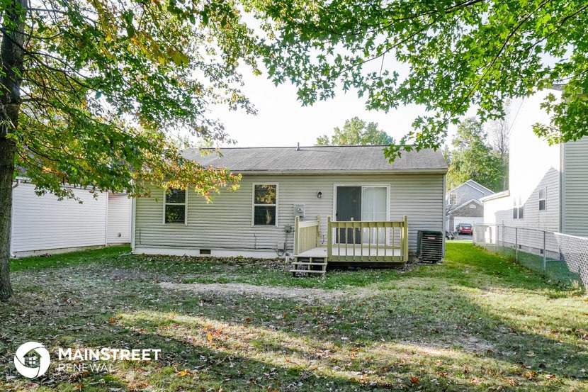 a white house with a porch and a bench in a yard