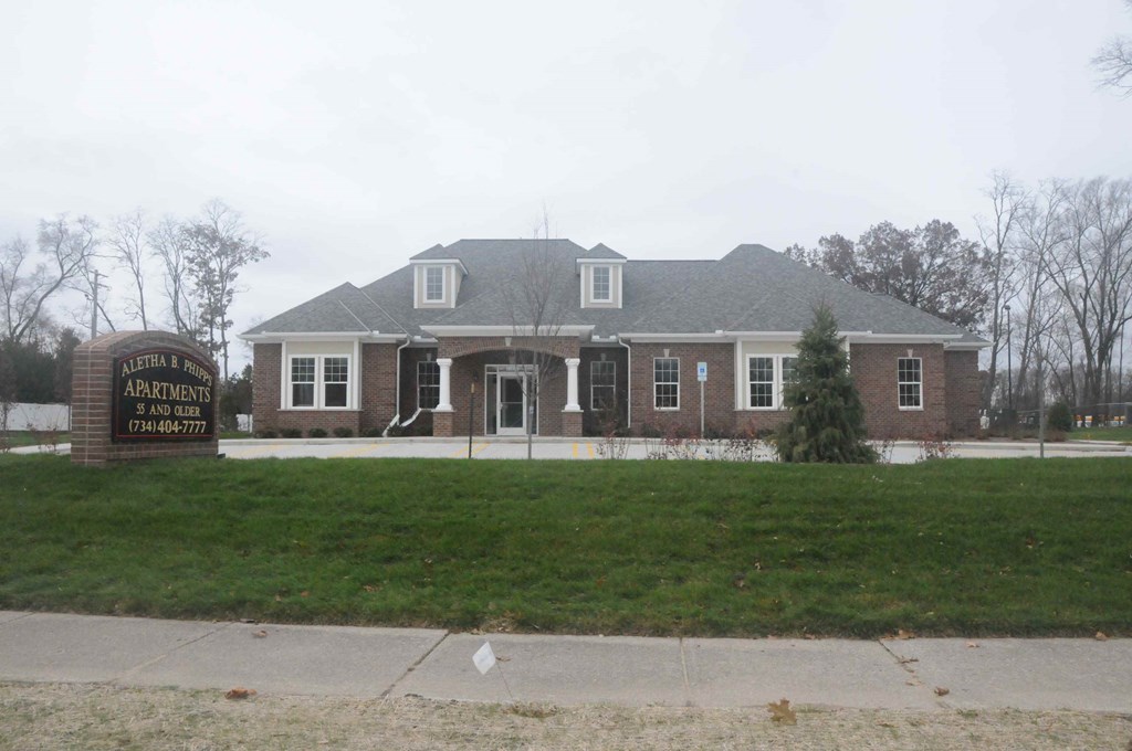 a view of the front of a brick house with a sidewalk and grass