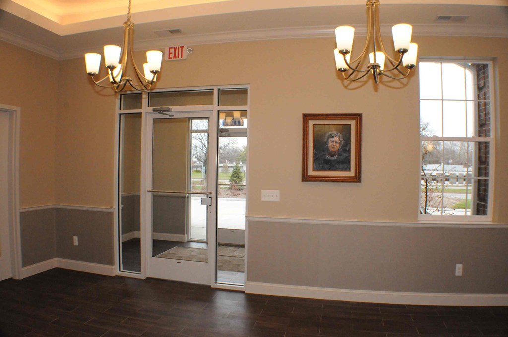 an empty dining room with a painting on the wall and chandeliers