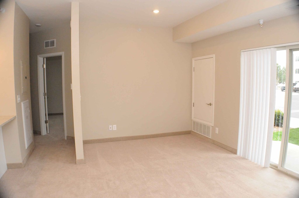 an empty living room with a door to a hallway