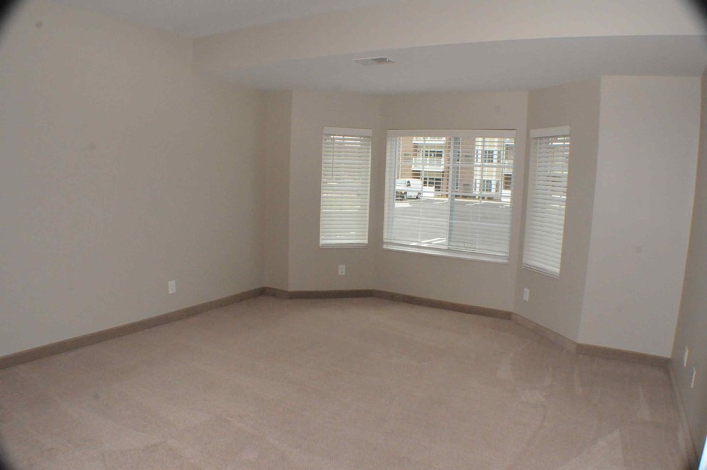an empty living room with three windows and a tiled floor