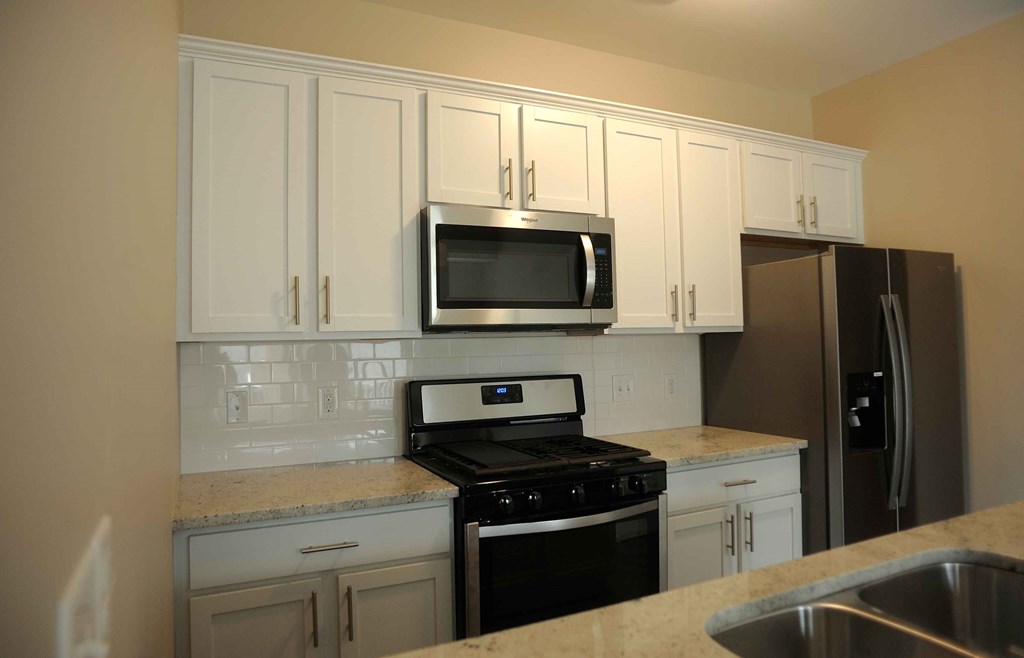 a kitchen with white cabinets and a stove and a microwave