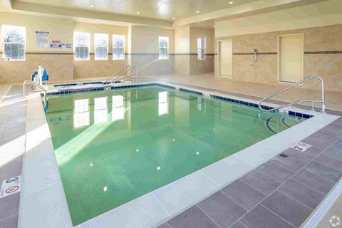 a swimming pool with green water and tan tiles