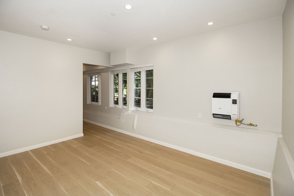 A room with a white wall and a wood floor.