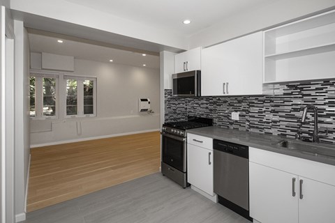 A modern kitchen with black and white appliances and wooden flooring.