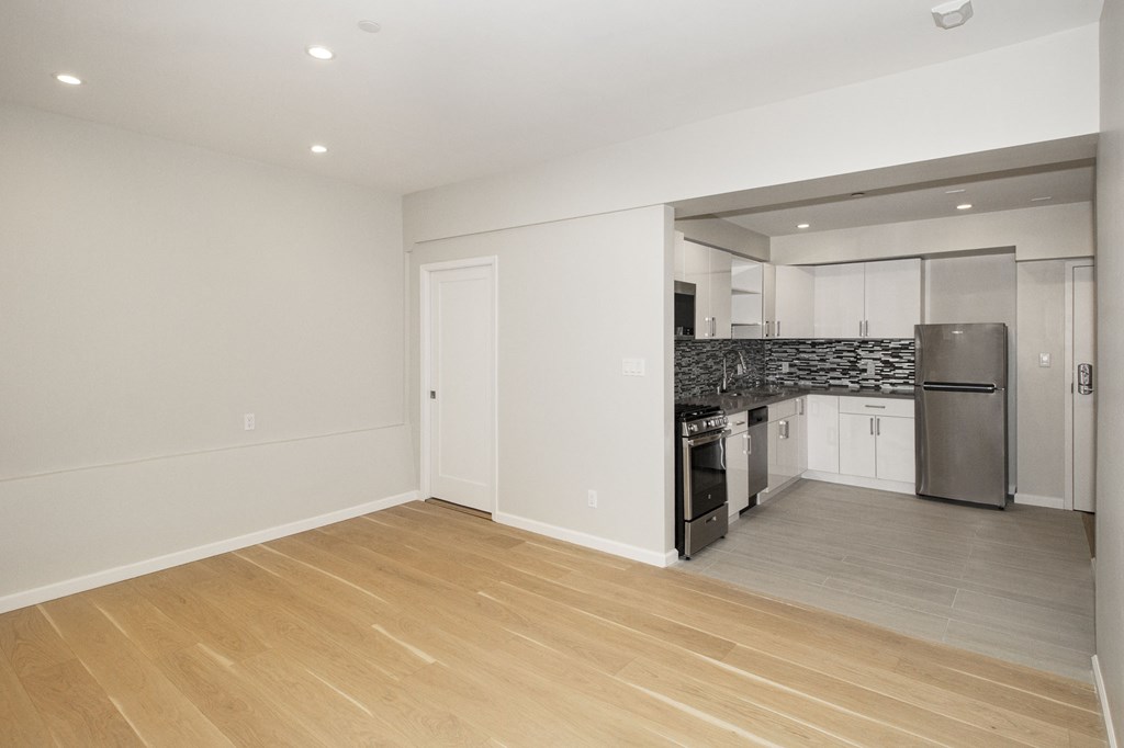 A kitchen with a refrigerator, oven, and sink.