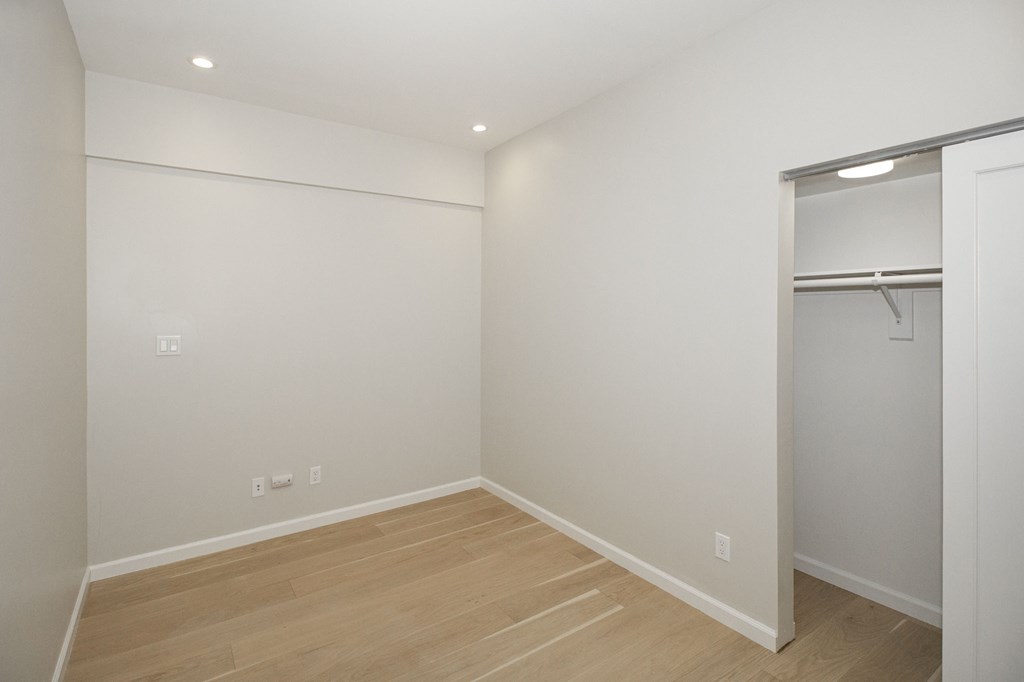 A room with a wooden floor and a closet with a white door.