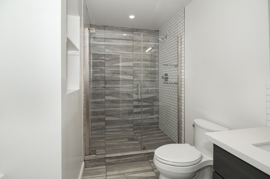 A white toilet sits next to a walk-in shower with a glass door.