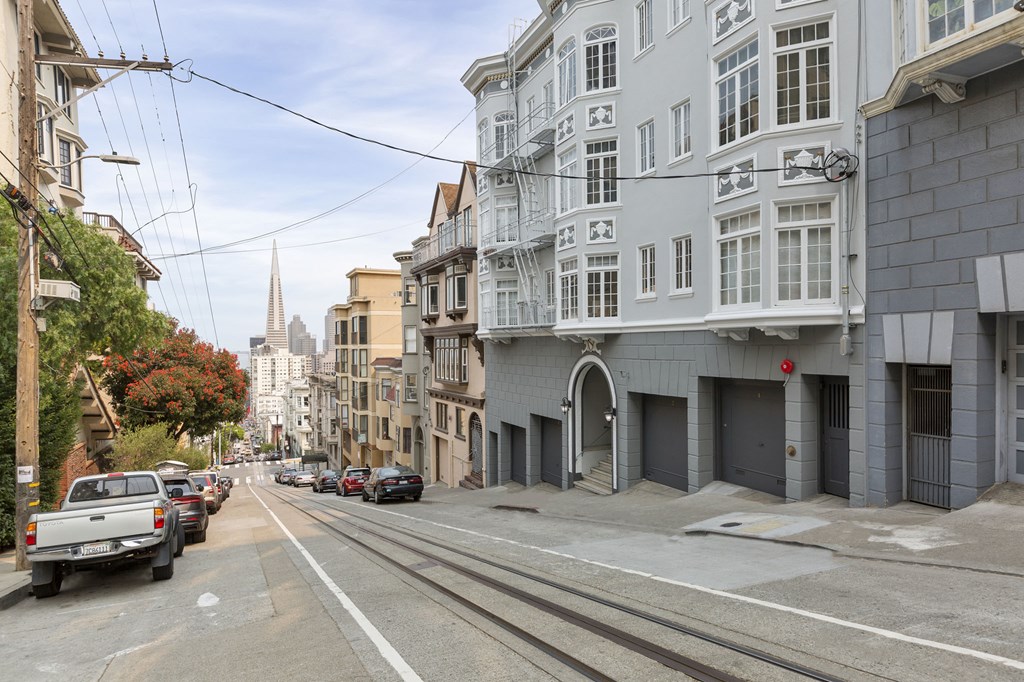 A street view of a city with buildings on both sides and cars parked on the side of the road.