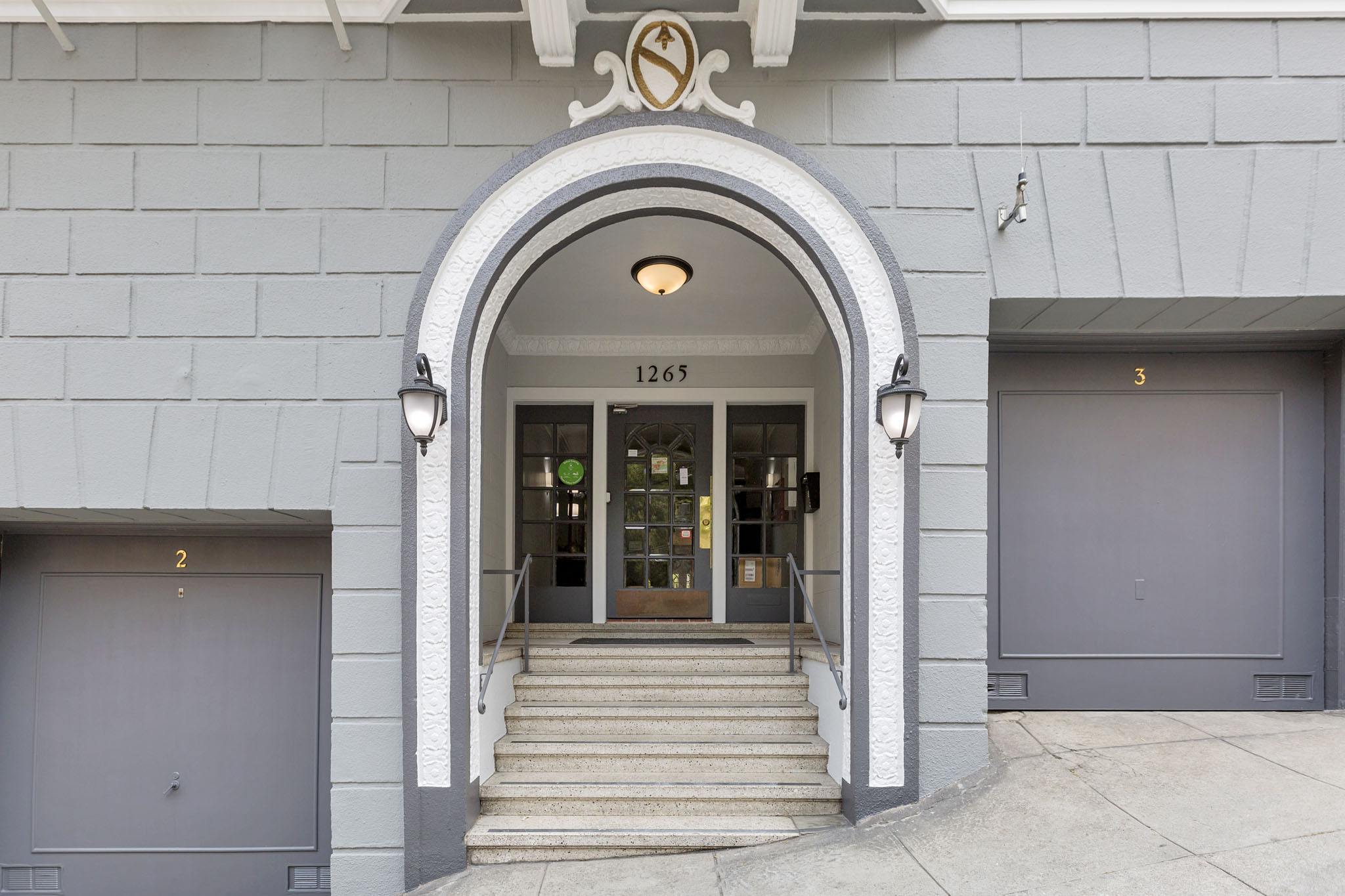 The entrance to a building with a grey facade and a large arched doorway.