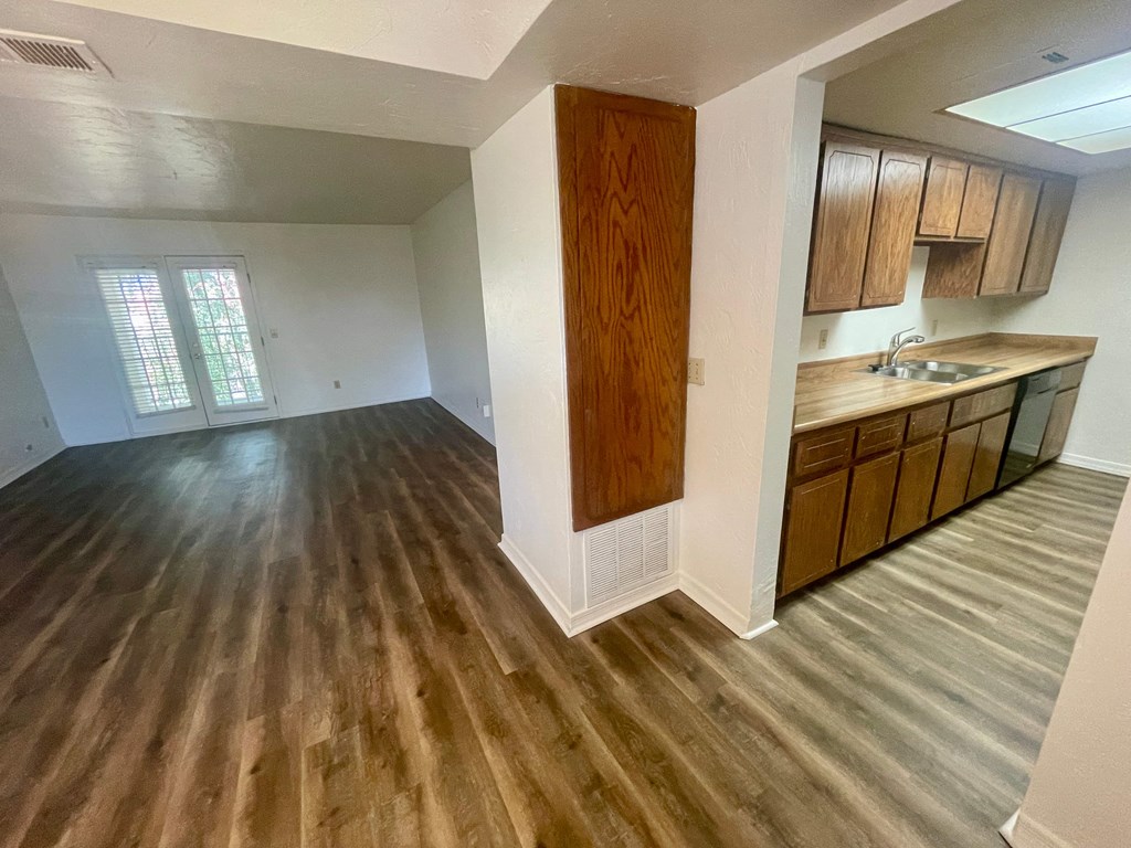 an empty living room and kitchen with wood flooring
