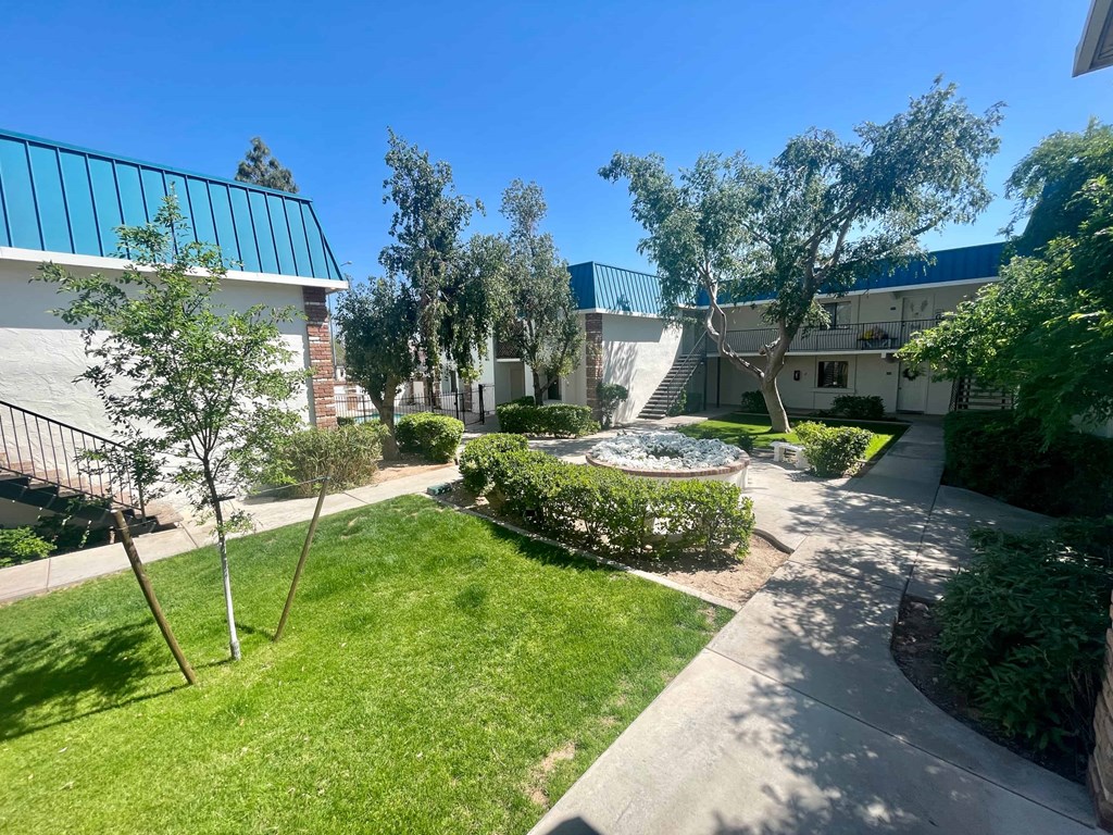 a courtyard with trees and a building in the background