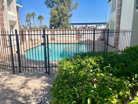 a wrought iron fence around a swimming pool in front of a house