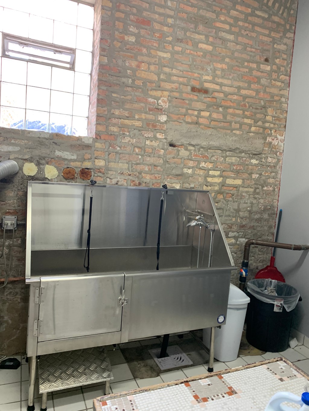 a stainless steel sink in a room with a brick wall