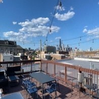 a rooftop deck with tables and chairs and a city in the background