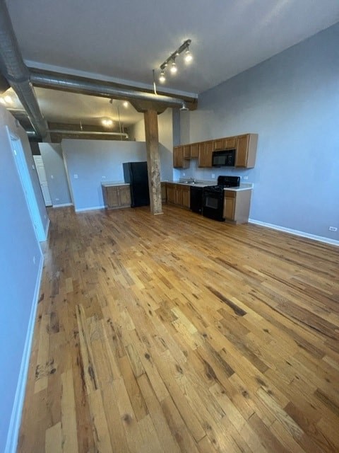 an empty living room and kitchen with wood floors