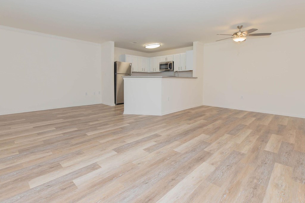 the living room and kitchen of an apartment with wood flooring