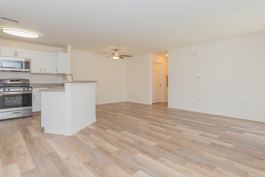 the living room and kitchen of an apartment with wood flooring