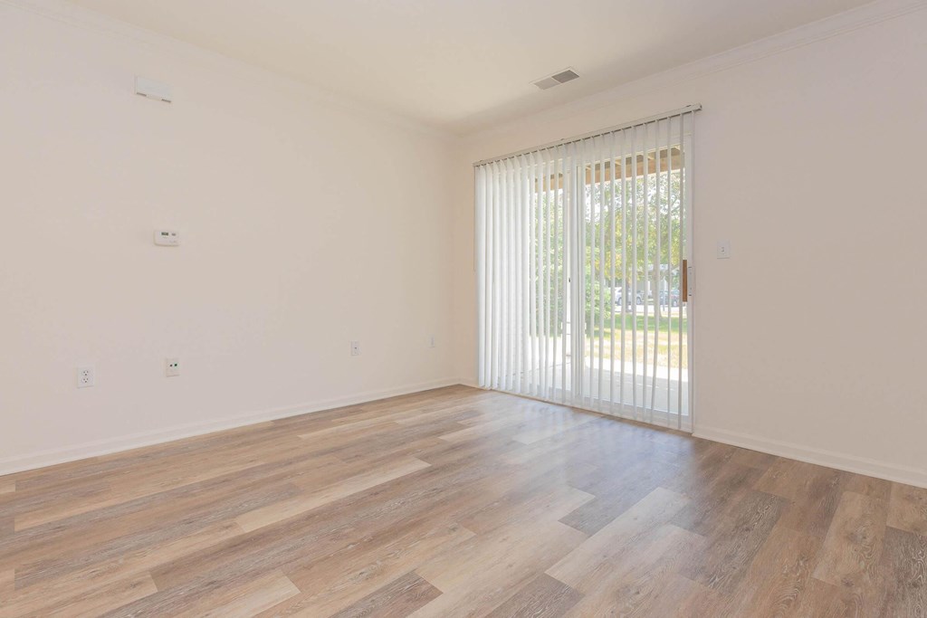 an empty living room with wood floors and a sliding glass door