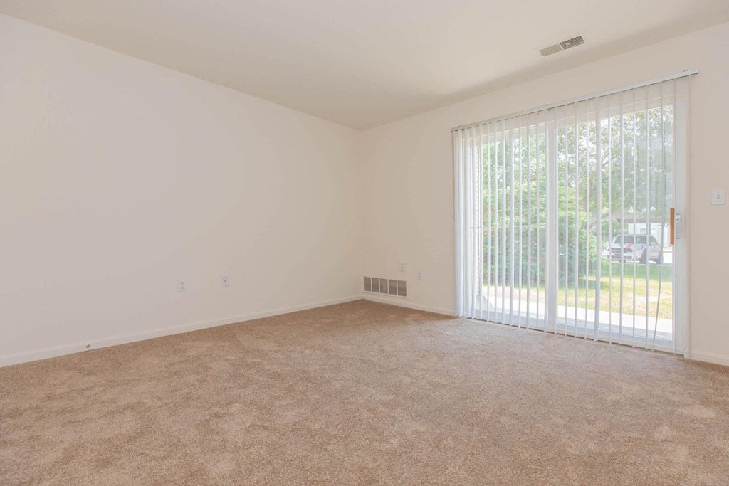 an empty living room with a large window and carpeting