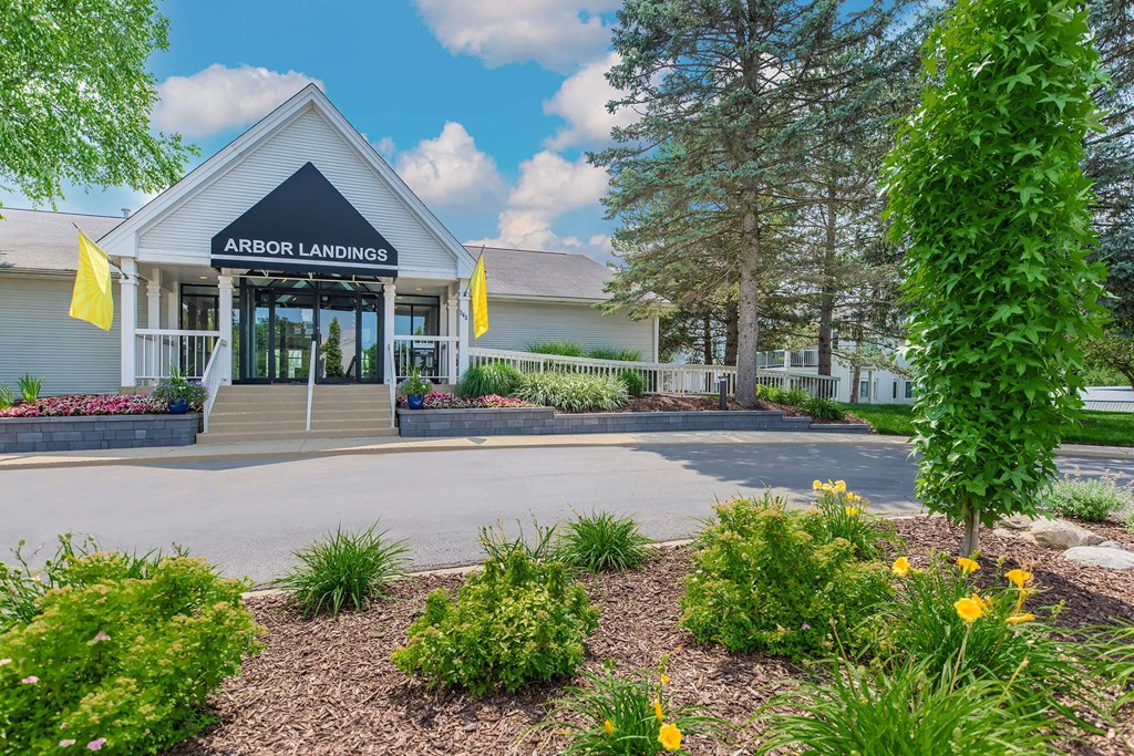 the front of the arbor landings office building with a driveway and landscaping