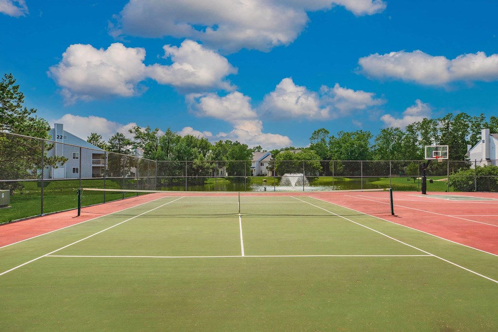 two tennis courts with buildings and trees in the background