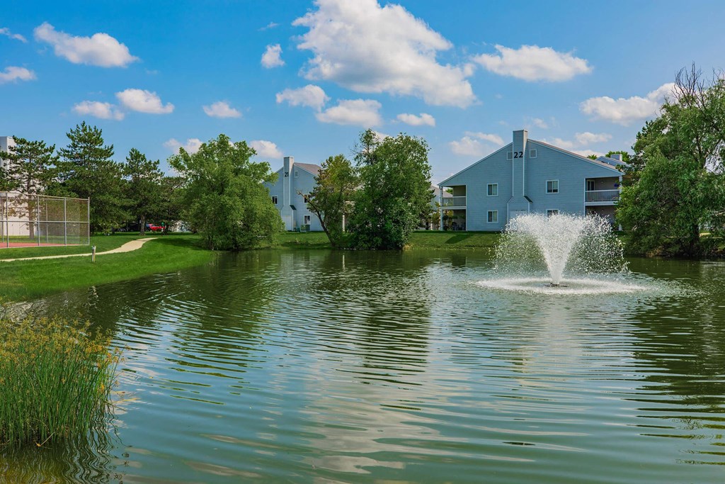 a fountain in the lake with a building in the background