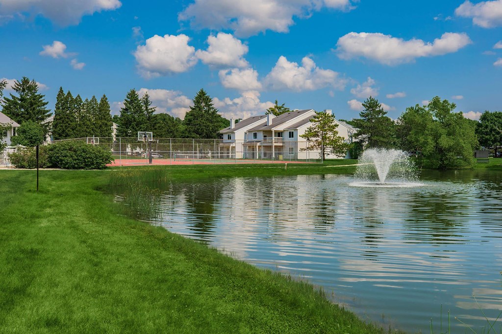 a fountain in the pond with a building in the background