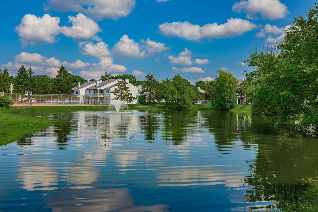 a pond with a fountain in front of a building