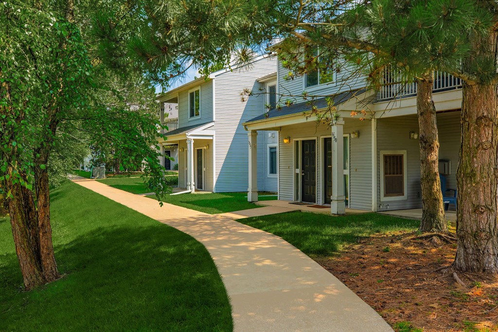 a sidewalk in front of a building with trees