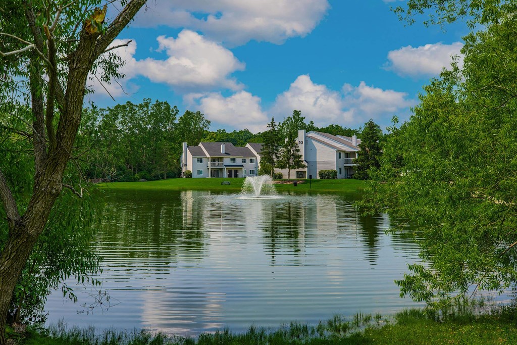 a fountain in the lake with a house in the background