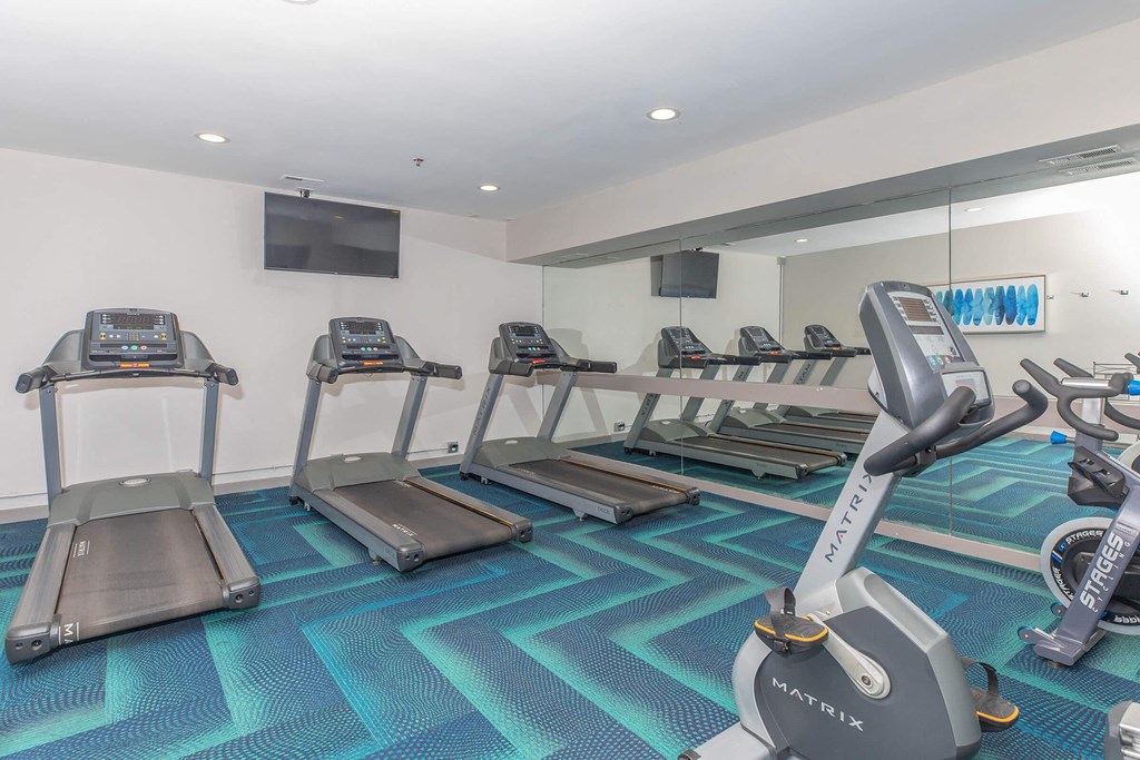 a gym with cardio equipment on the floor and mirrors