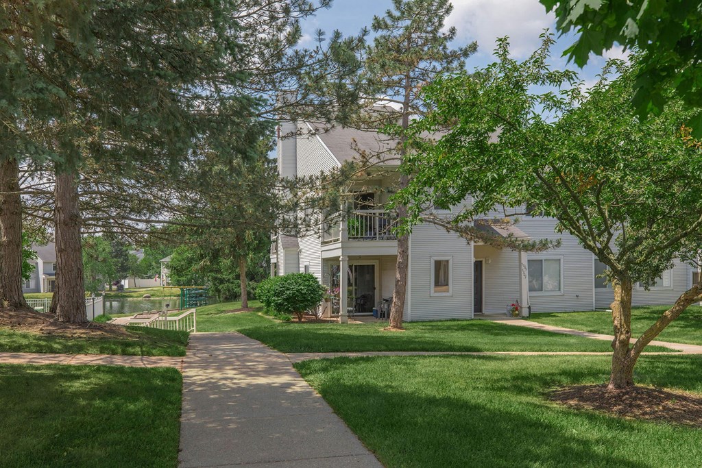 a white house with trees and a sidewalk