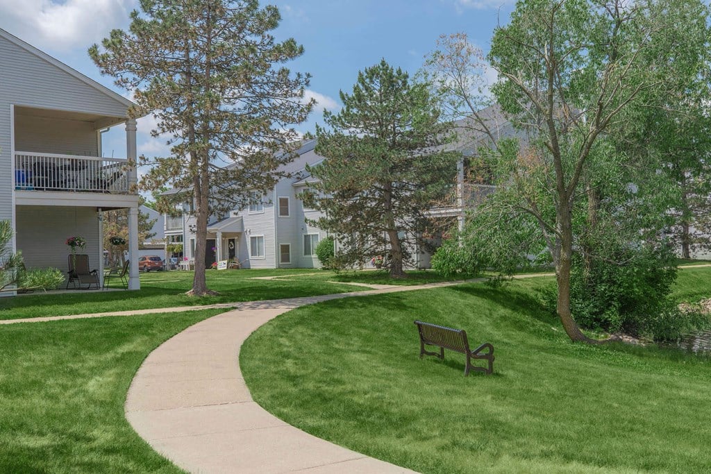 a park bench sitting in the grass in front of some houses