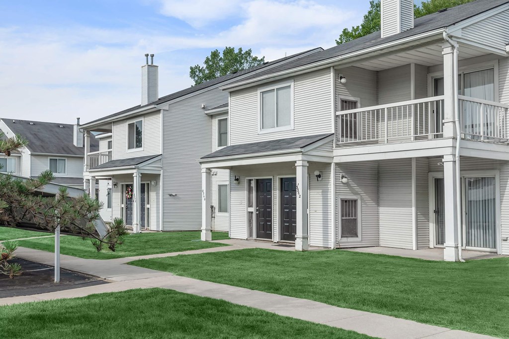 a group of white houses with a yard and grass
