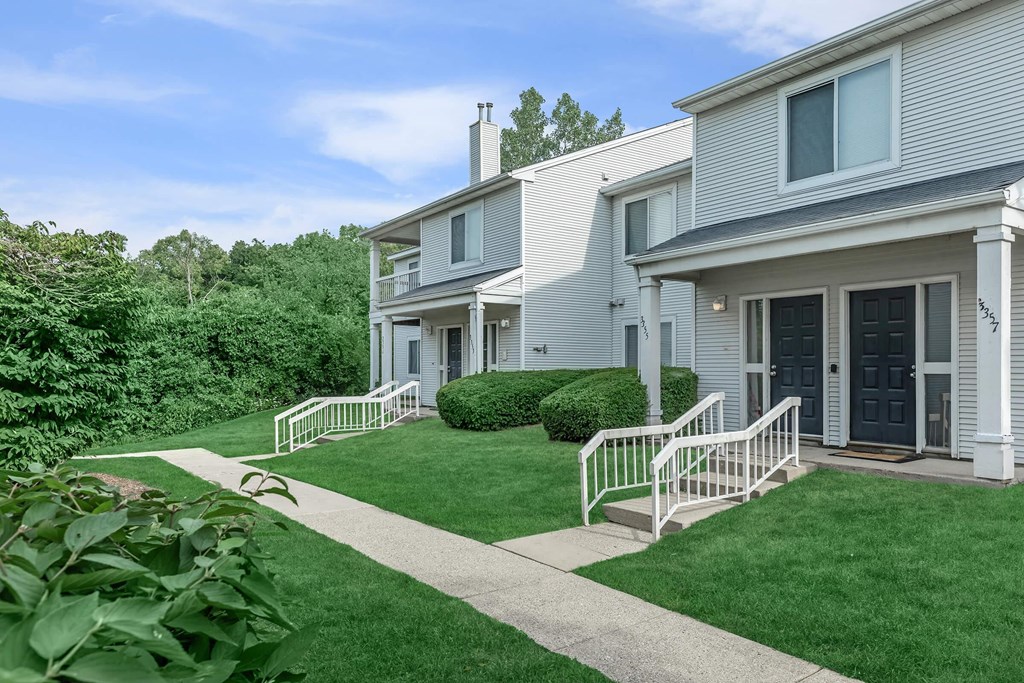 the front of a white house with a yard and stairs