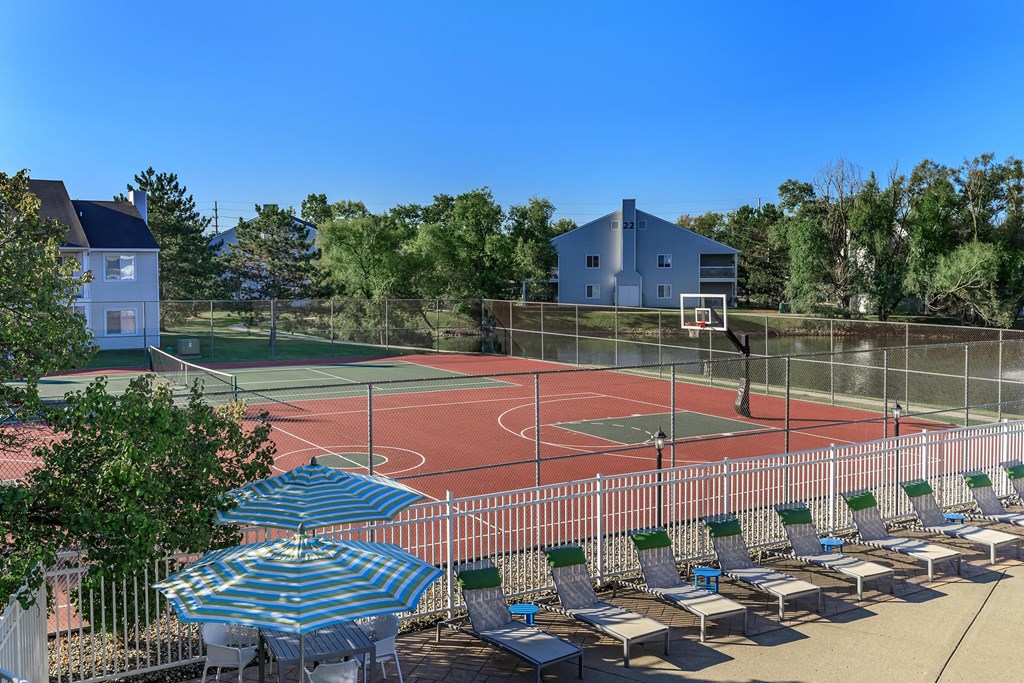 an outdoor tennis court with chairs and umbrellas