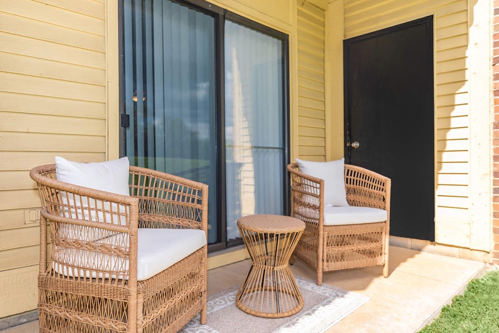 a porch with two rattan chairs and a coffee table
