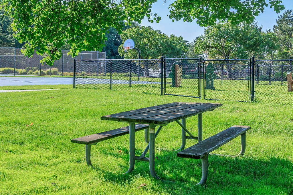 two picnic tables in the grass in front of a playground