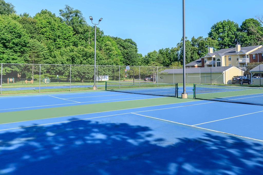two tennis courts with houses and trees in the background
