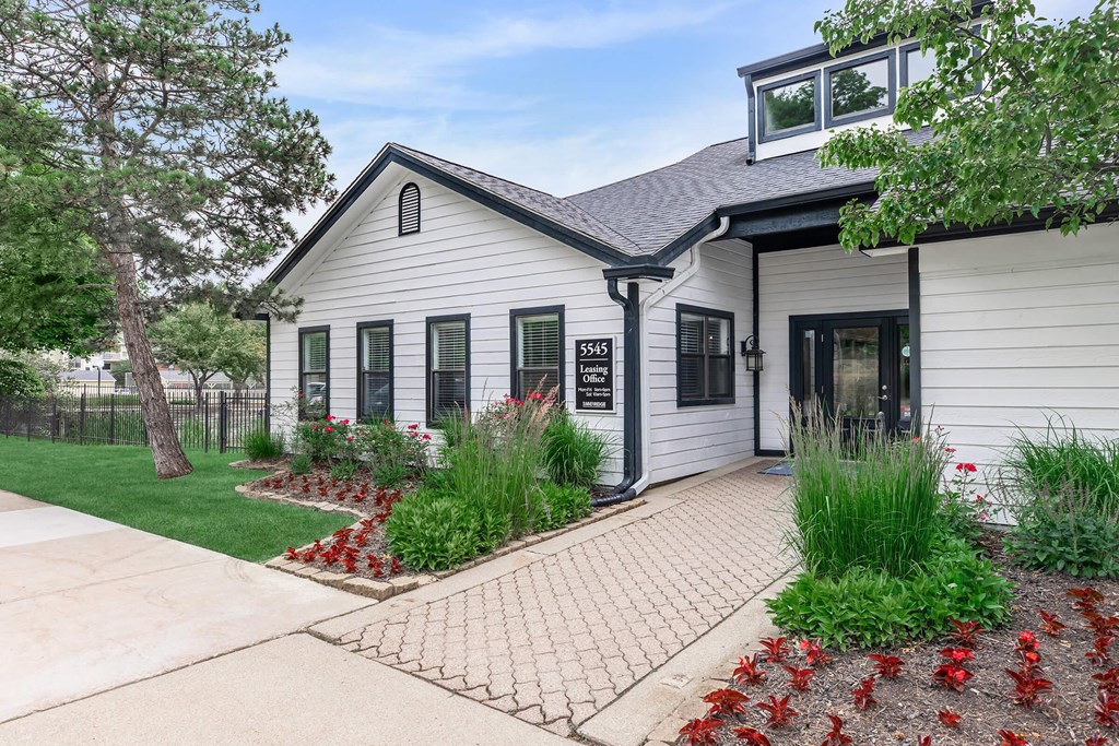 the front of a white house with a sidewalk and landscaped yard