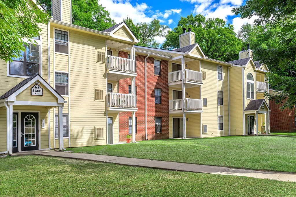 an exterior view of an apartment building with a grass lawn and trees