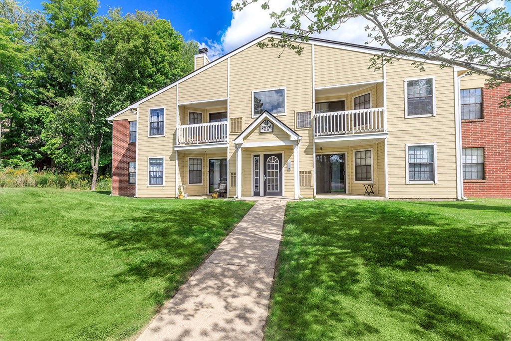 the front of a house with a lawn and a walkway
